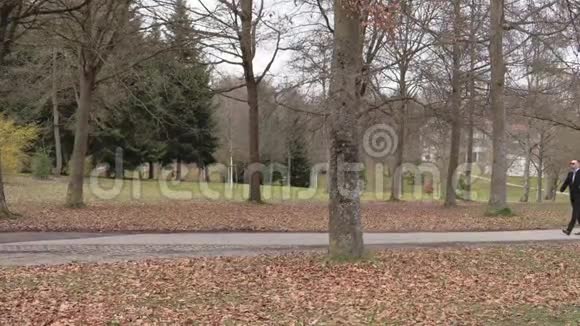 穿着黑色夹克在秋天公园散步的人视频的预览图