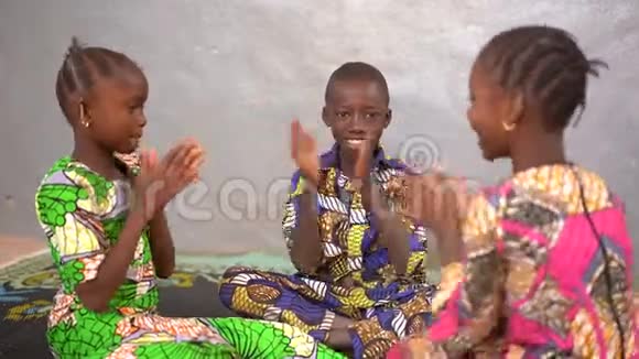 英俊的非洲小男孩和两个女孩玩手拍游戏视频的预览图
