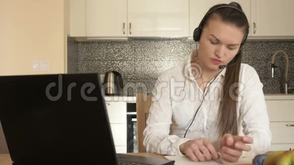 在家工作的年轻女人坐在厨房的桌子旁看着笔记本电脑的屏幕写下一些东西能力视频的预览图