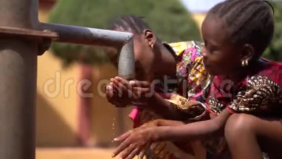 两个穿着漂亮的非洲小女孩从水龙头里取水视频的预览图