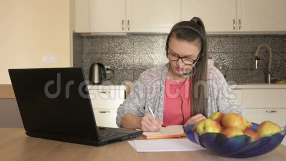 年轻女性带耳机笔记本电脑前桌在线客户咨询视频的预览图