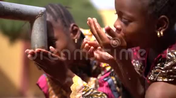 两个有趣的非洲小女孩在村里的水泵旁玩水视频的预览图
