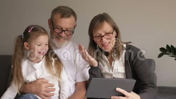 孩子和祖父母使用PC平板电脑可爱的中年夫妇和他们的小孙女用数码平板电脑视频的预览图