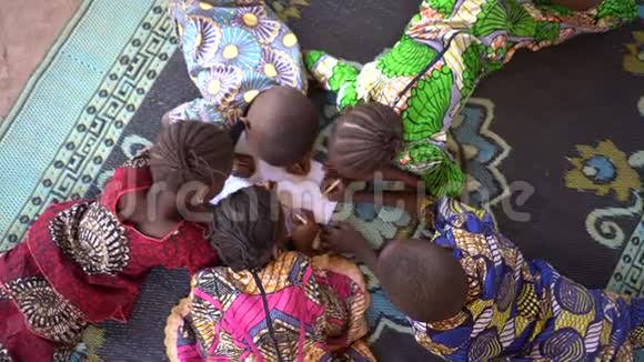 鸟瞰五个躺在地毯上的非洲小孩在一张纸上做设计视频的预览图