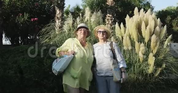 两位戴帽子的老年妇女在度假时站在棕榈树附近视频的预览图