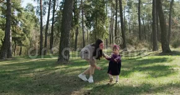 快乐的小女孩在针叶林的树上和妈妈散步玩耍健康儿童家庭娱乐视频的预览图