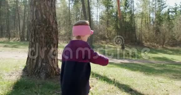 快乐的小女孩在针叶林中的树林中绿草如茵地散步与社会隔绝的健康儿童娱乐活动视频的预览图