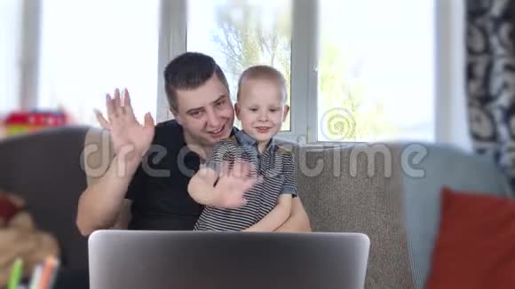 爸爸和儿子正在看手提电脑与亲属视频通话爸爸和儿子挥手你好走进笔记本电脑和祖父母交谈视频的预览图