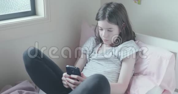 年轻女孩在床上用手机视频的预览图