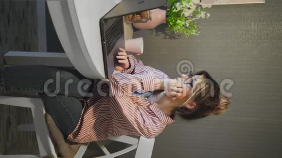 视频年轻女性通过电话会议交流说话看电脑喝咖啡视频的预览图
