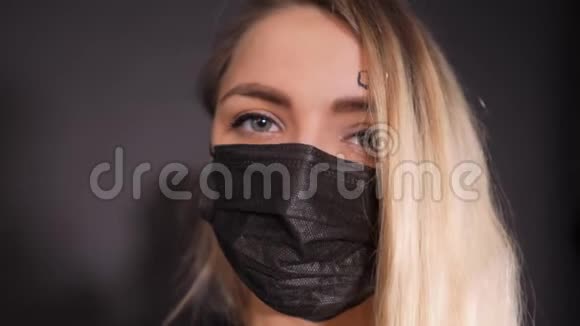 戴着黑色防护面罩的女人额头上写covid19的单词女孩从她的头发上推开一把视频的预览图