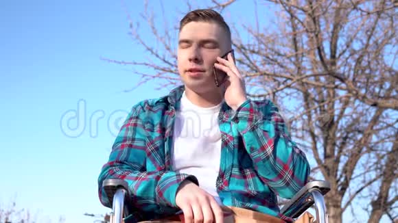 一个坐在轮椅上的年轻人在打电话有智能手机的残疾人视频的预览图