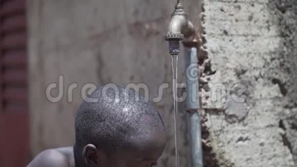 贫穷象征年轻的非洲黑人儿童喝自来水从户外缓慢运动视频的预览图