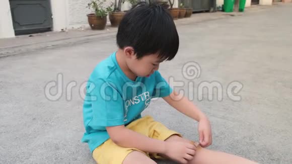 一个亚洲男孩骑着自行车摔倒在膝盖上画画他用医用石膏保护自己的血液视频的预览图