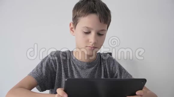 男孩拿着数字平板电脑看视频在线学习玩游戏视频的预览图