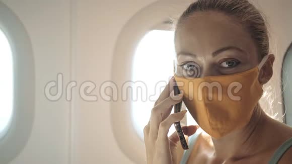 女旅游白种人在飞机上戴着防护医疗面罩阅读有关鸡冠状病毒的震惊新闻视频的预览图