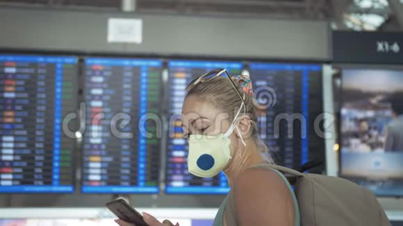 女白种人在苏瓦纳布胡米机场戴着防护医疗面罩飞行信息委员会使用智能手机视频的预览图