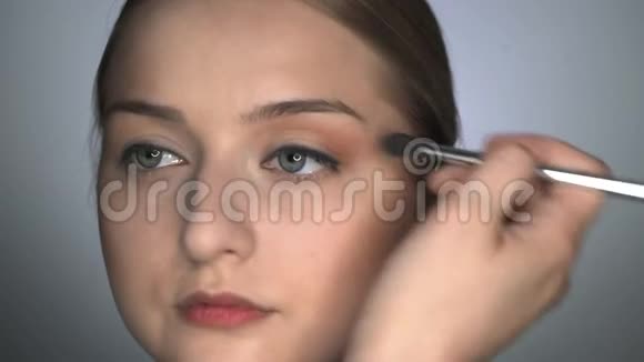 化妆师为美容工作室的年轻女性制作专业化妆化妆师用刷子涂上腮红视频的预览图