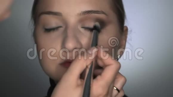化妆师在美容工作室为年轻女性做专业化妆的正面视图化妆师用刷子视频的预览图