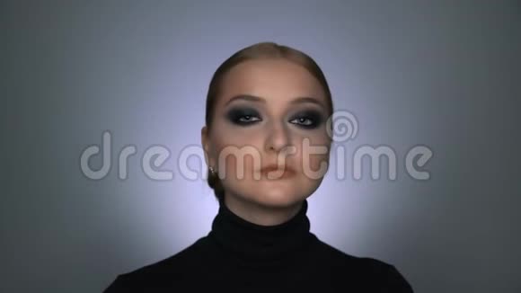 美丽的女人化妆烟雾般的眼睛在镜头前摆姿势视频的预览图