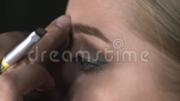 化妆师在美容工作室为年轻女性做专业化妆的宏观镜头化妆师的眉毛视频的预览图