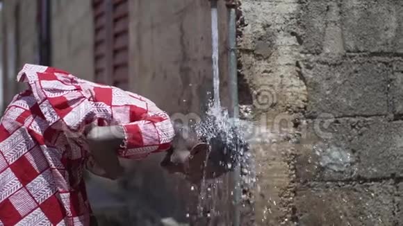美丽的非洲女孩在马里巴马科的一个户外水龙头下洗头视频的预览图