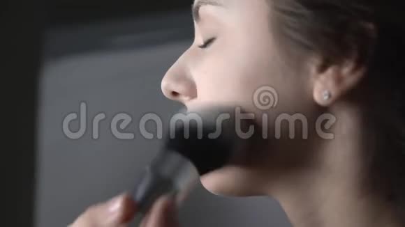 为坐在工作室的漂亮漂亮女人做专业化妆的过程化妆师使用粉末视频的预览图