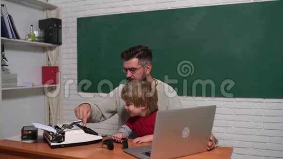 父子俩用旧打字机和笔记本电脑打字技术进步老年人和年轻人旧打字机和笔记本电脑视频的预览图