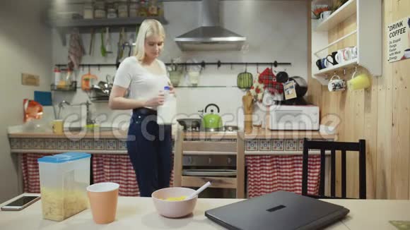 年轻的女人在家里的厨房里工作电脑吃玉米片视频的预览图