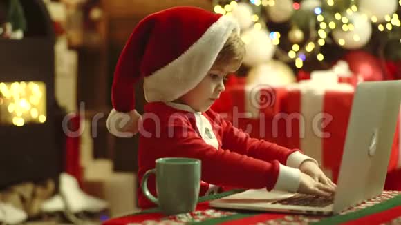 网上商店网上圣诞商店打折快乐可爱的孩子戴着圣诞老人的帽子和笔记本电脑视频的预览图