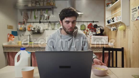 自由职业者工作笔记本电脑和吃玉米片谷物在家庭厨房视频的预览图