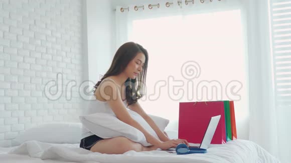 女人躺在床上用电脑笔记本电脑使用社交媒体和网上购物持有信用卡视频的预览图