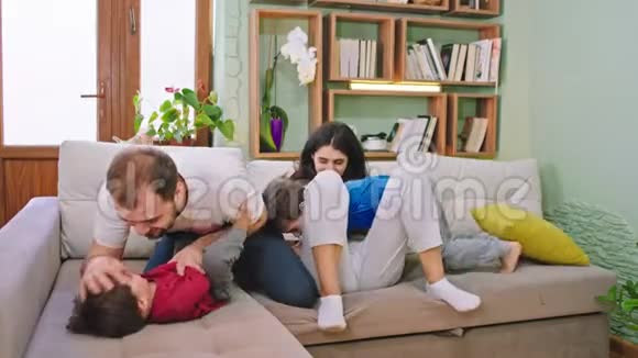 在家里的沙发上一家人和两个孩子在一起玩得很开心他们感到快乐和兴奋视频的预览图