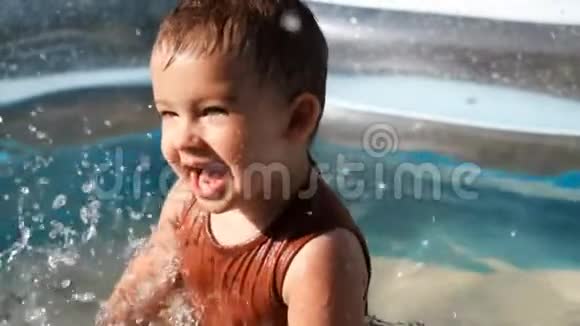 快乐的白人小男孩在游泳池里玩耍的慢动作视频的预览图