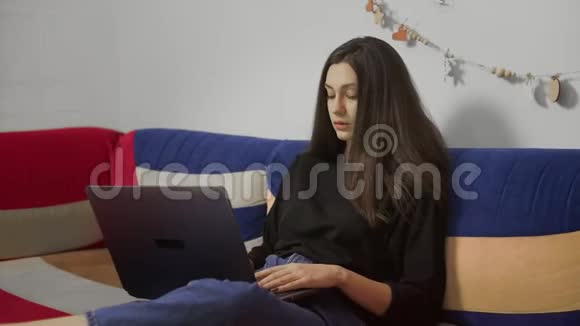 年轻的自由职业者在笔记本电脑上工作坐在舒适的沙发上在家工作的自由职业者视频的预览图