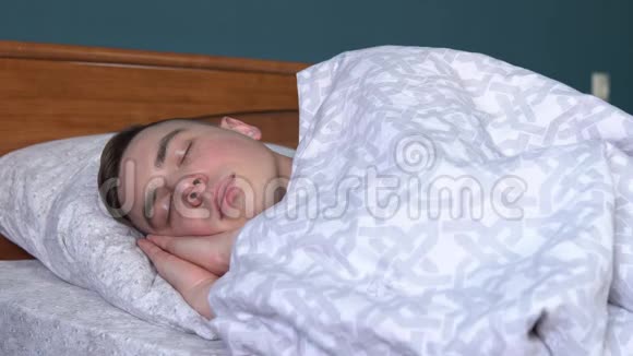 一个年轻人睡在被子下一个人躺在他房间的床上视频的预览图