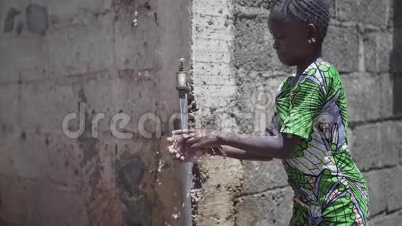 美丽的非洲黑人少女在室外用淡水洗手视频的预览图