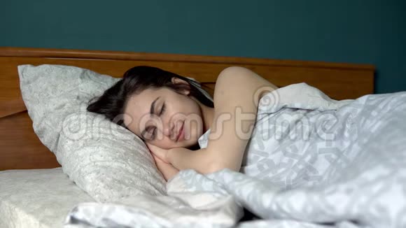 年轻的女人醒来了那个女人睡在她房间的床上视频的预览图