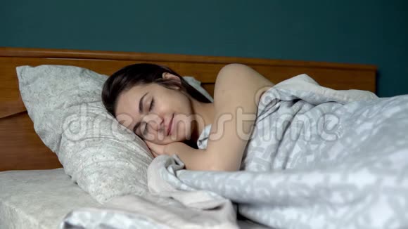 一个年轻的女人睡在被子下一个女孩躺在他房间的床上视频的预览图