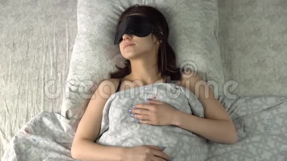 一个年轻的女人睡在睡眠面具里一个女孩躺在他房间的床上从上面看视频的预览图