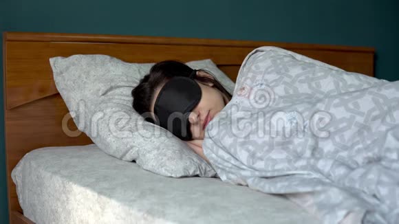 一个年轻的女人睡在睡眠面具里一个女孩躺在他房间的床上视频的预览图