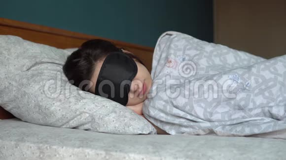 一个年轻的女人睡在睡眠面具里一个女孩躺在他房间的床上视频的预览图