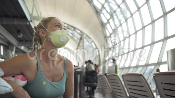 女子白种人在机场头上戴着防护医疗面罩飞机背景冠状病毒视频的预览图