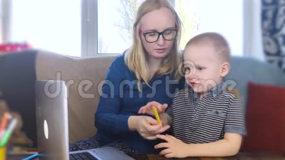学龄前儿童从事家庭教育这个男孩坐在一张桌子旁在网上写作画画和学习检疫到期视频的预览图