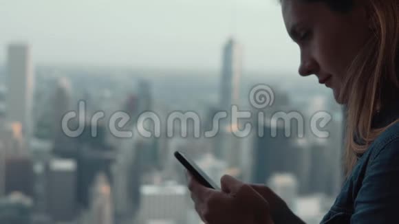 美国芝加哥摩天大楼的窗户附近年轻的黑发女人使用智能手机的肖像视频的预览图