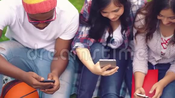 不同种族的朋友坐着看智能手机视频的预览图