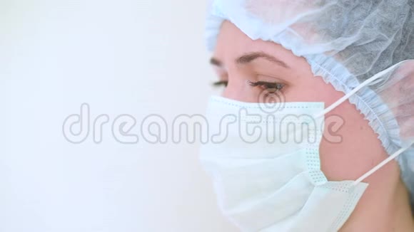 年轻的女医生或护士戴着医疗面具悲伤的眼睛在白色的背景上冠状病毒疾病covid19视频的预览图