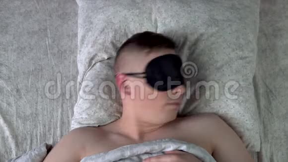 年轻人戴着睡眠面具睡不着一个人躺在房间的床上患有失眠症从上面看视频的预览图
