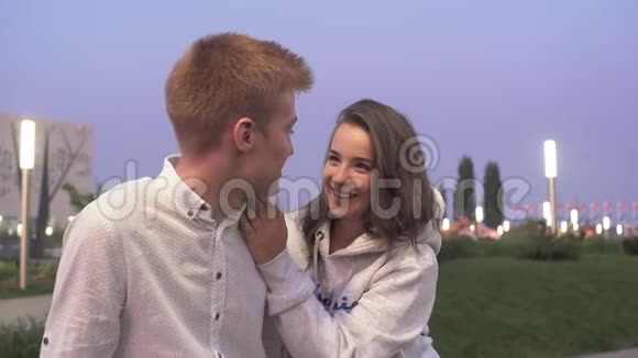 晚上年轻可爱的一对夫妇坐在夏天的公园里聊天视频的预览图
