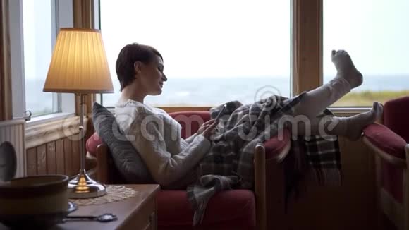 一个女人在家里的沙发上使用智能手机视频的预览图